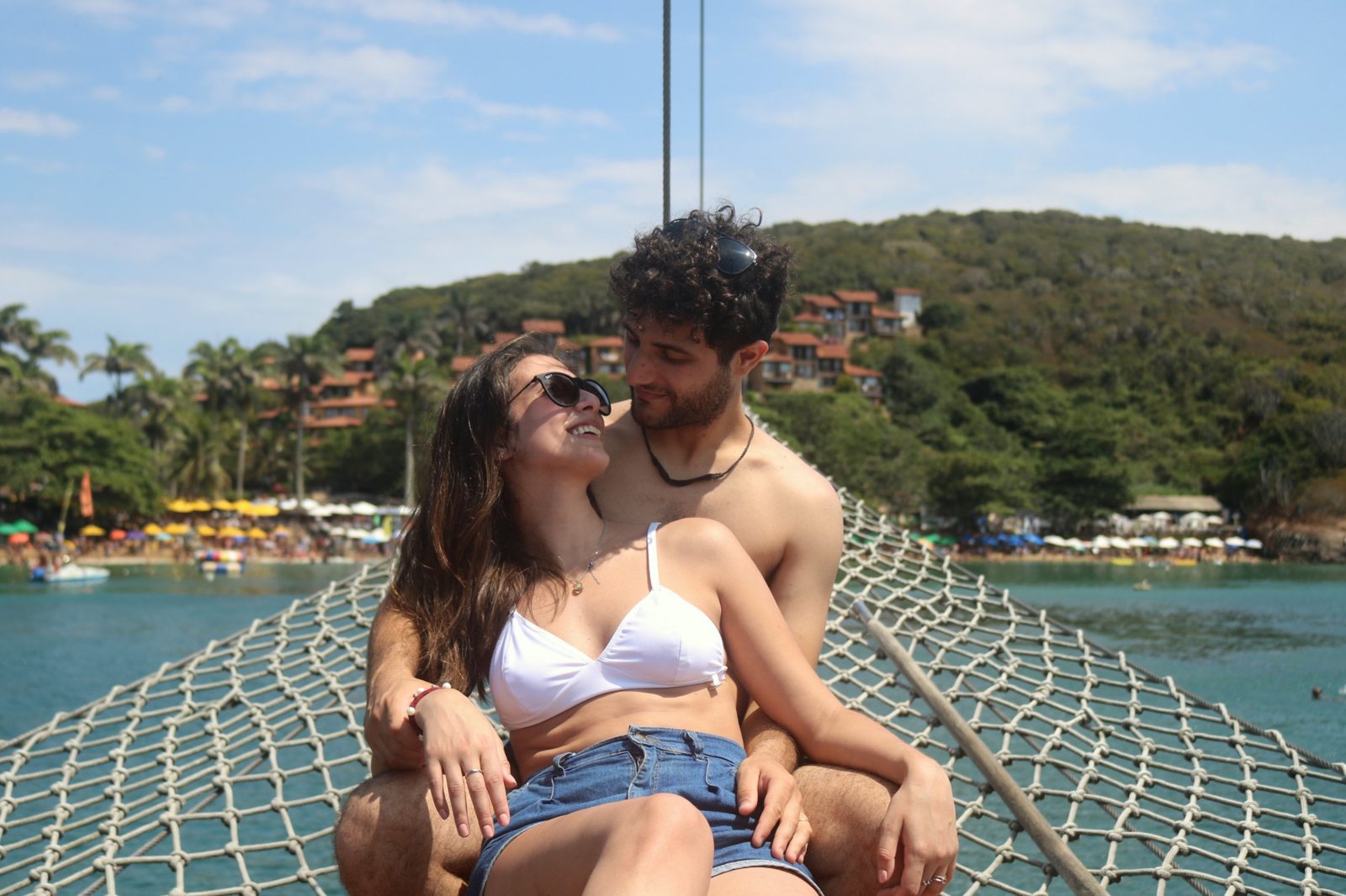 Pareja abrazada en la proa de un barco frente a una playa de Búzios