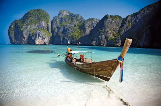Bote tradicional de cola larga en una playa de agua turquesa en Tailandia